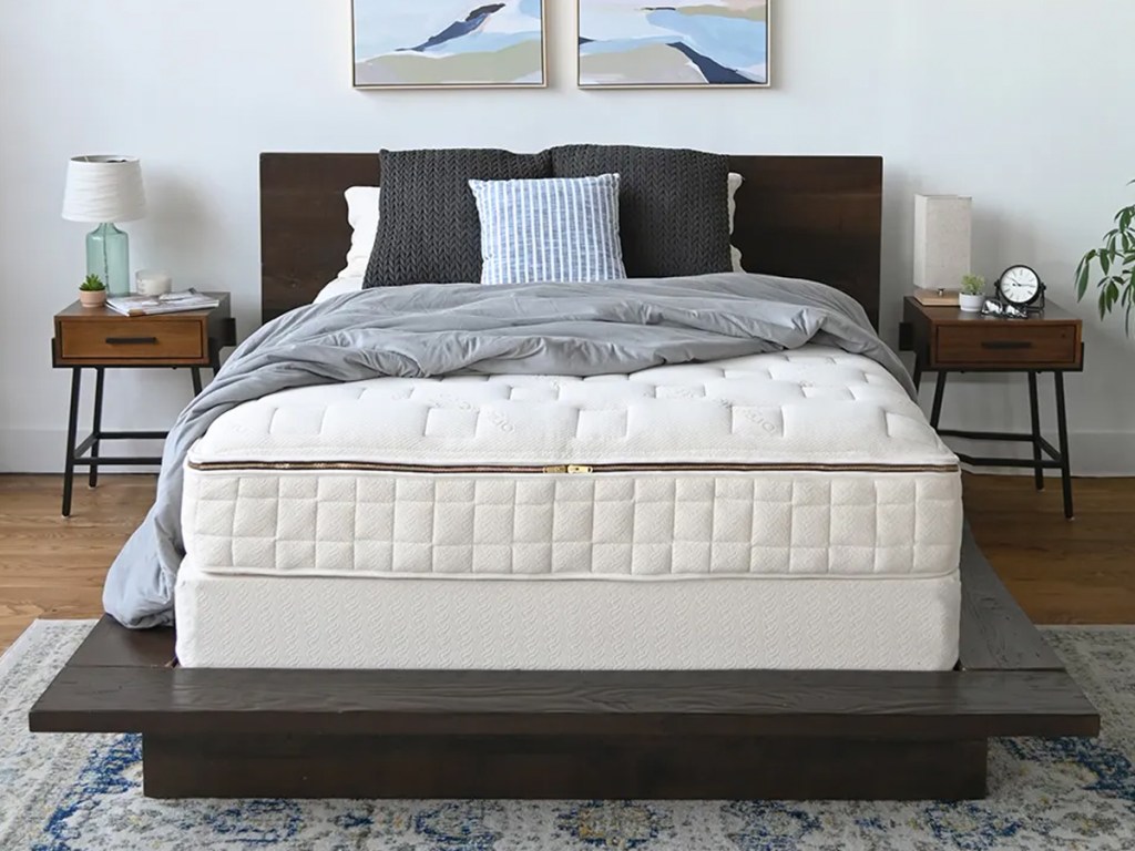mattress on a short dark brown bed frame with matching headboard and grey throw pillows