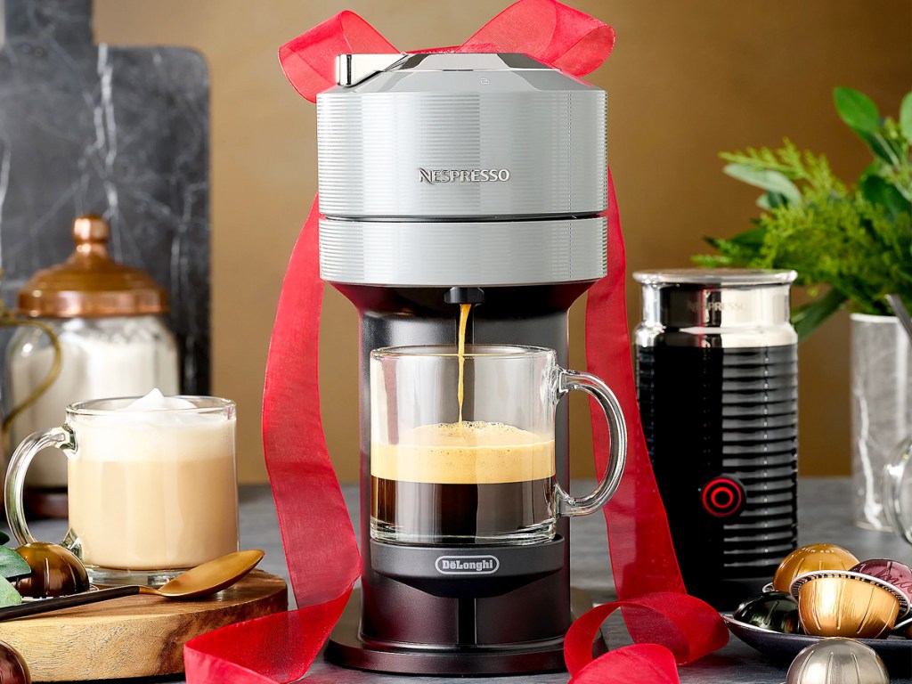 Nespresso Vertuo Next machine with red bow on top and milk frother in background