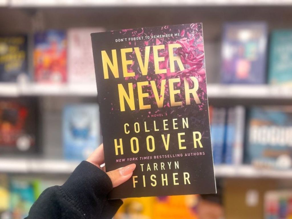 A hand holding Never Never by Collen Hoover