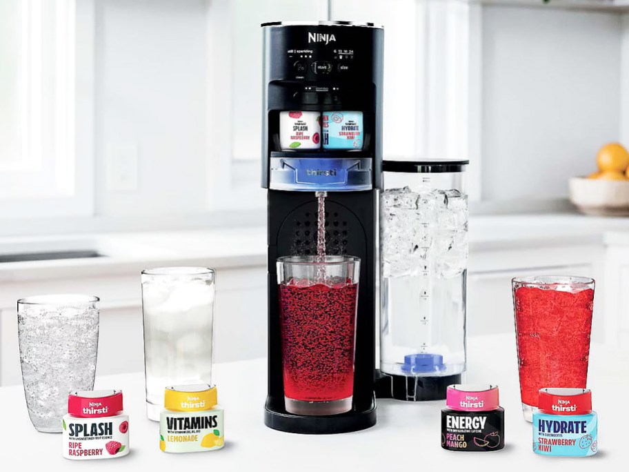 Ninja Thirsti Drink System on counter with multiple glasses of drinks and flavor drops