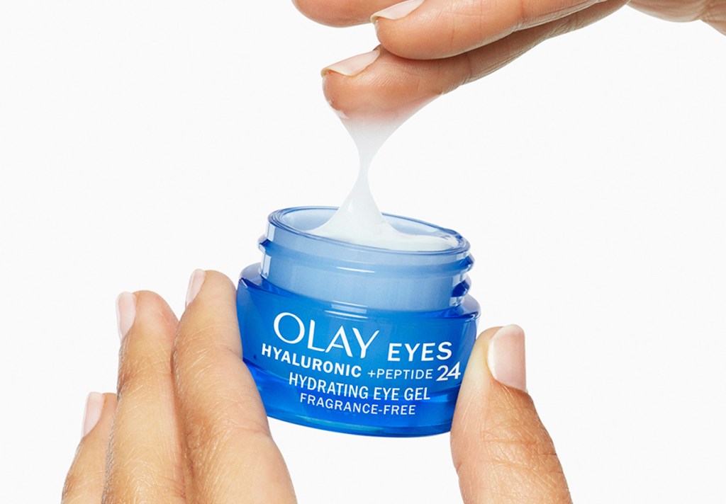 hand touching and holding blue jar of Olay Hyaluronic + Peptide 24 Gel Eye Cream