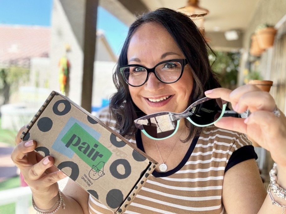 woman holding up glasses toppers and pair eyewear box