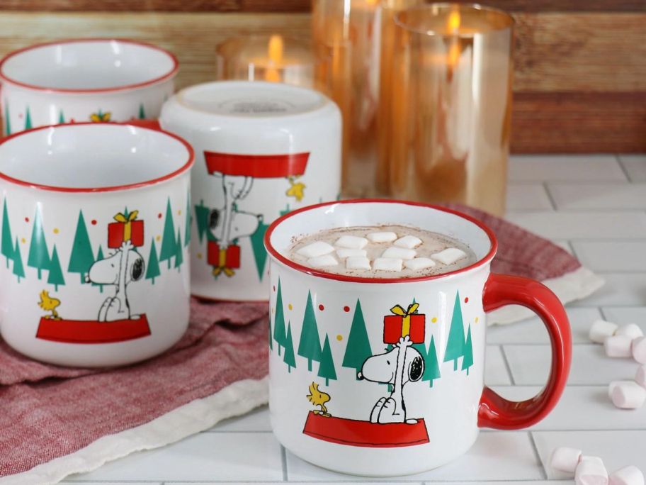 Peanuts Snoopy & Woodstock 4-Piece 21oz Stoneware Christmas Tree Mug Set on counter with hot chocolate in one of them