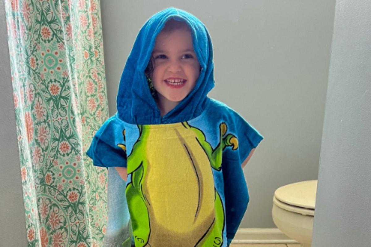 Young child in a character poncho beach towel