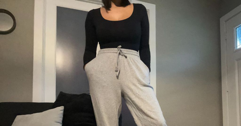 woman wearing black scoop neck long sleeve bodysuit with gray joggers