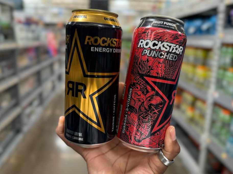A hand holding 2 Rockstar Energy Drinks