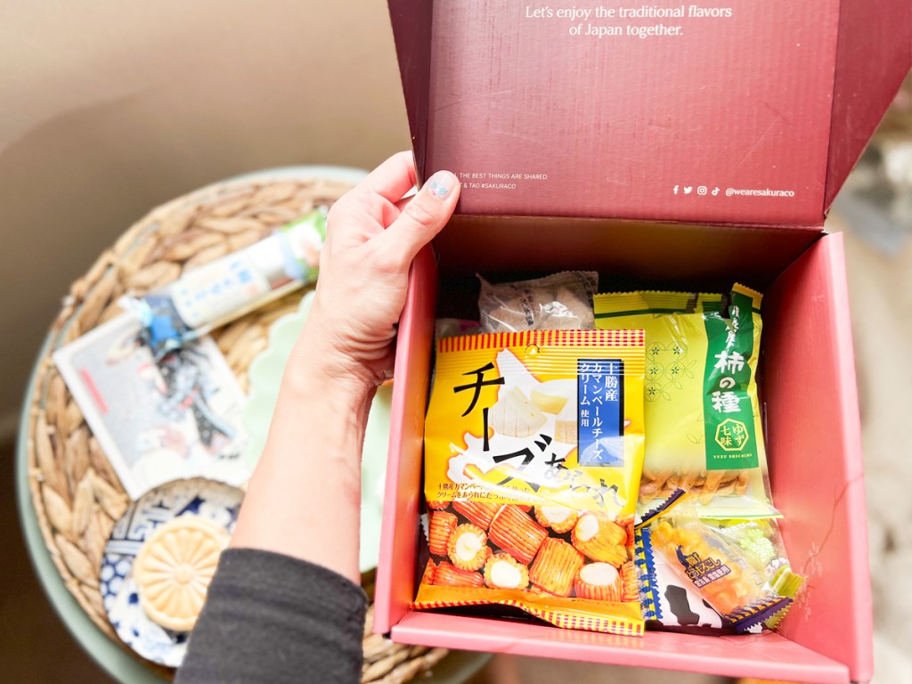 hands holding a box full of japanese snacks