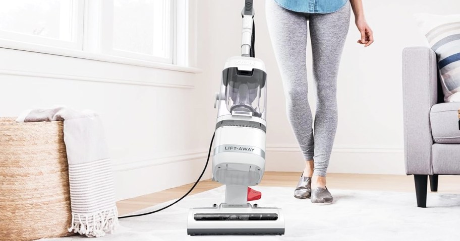 woman using white vacuum on area rug