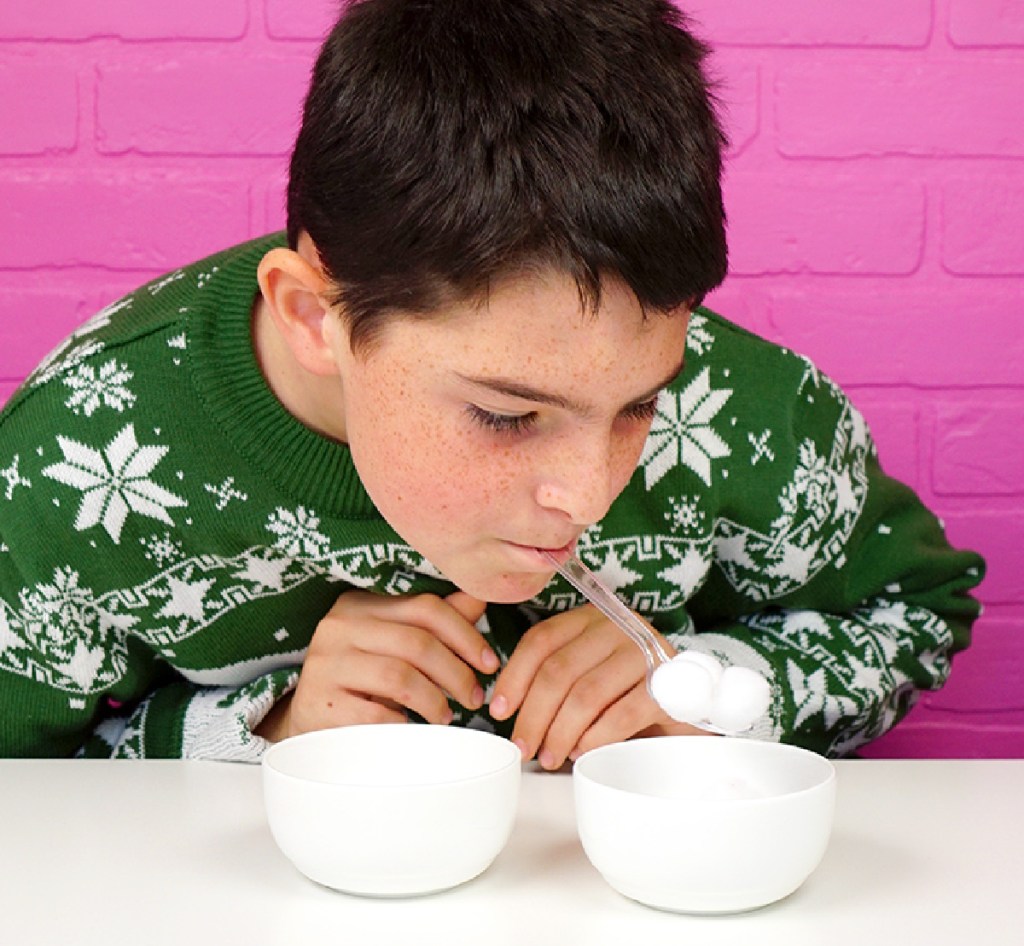 Boy using a spoon to move cotton balls from one bowl to another