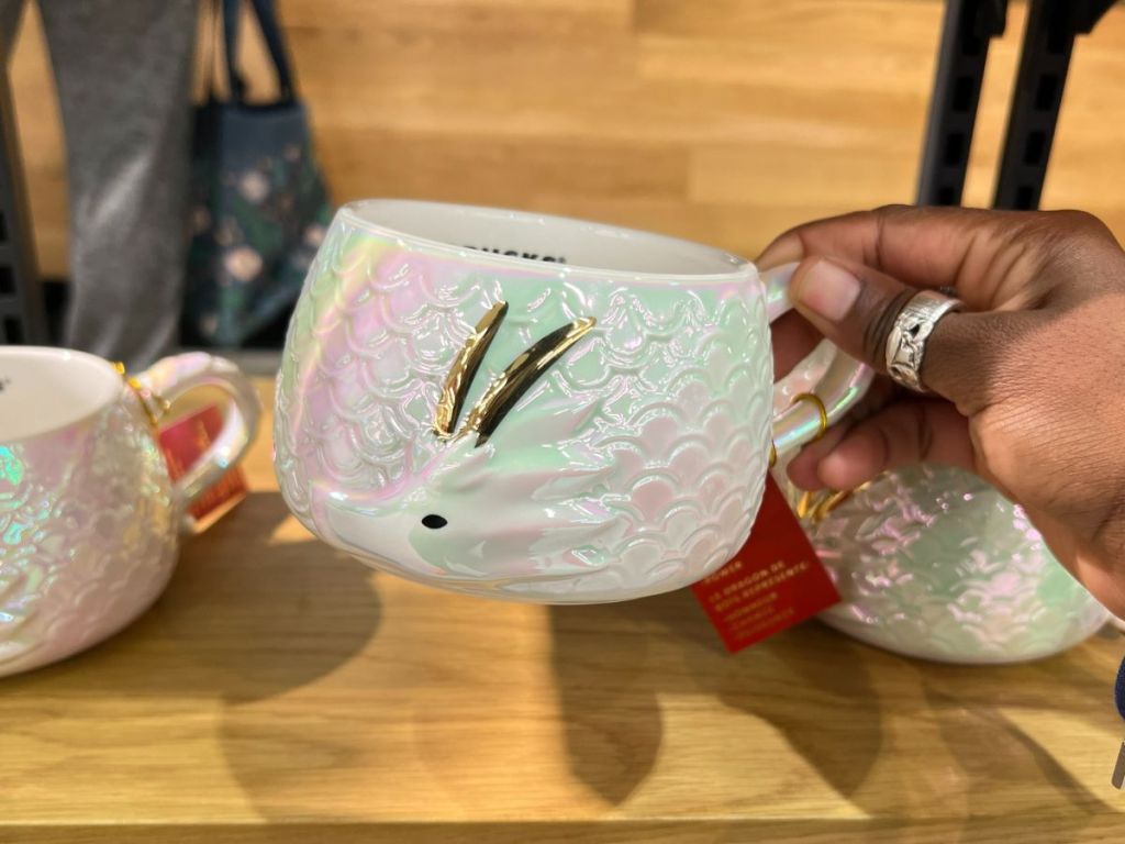 Starbucks irridescent and gold with Dragon head mug in person's hand 