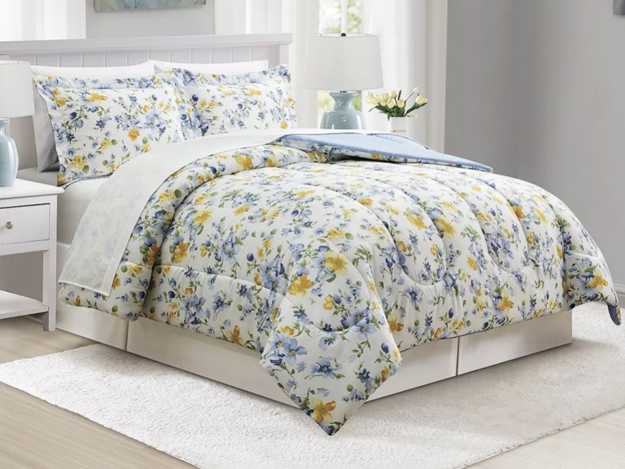 blue and yellow floral print comforter on bed with matching pillow shams and white sheets