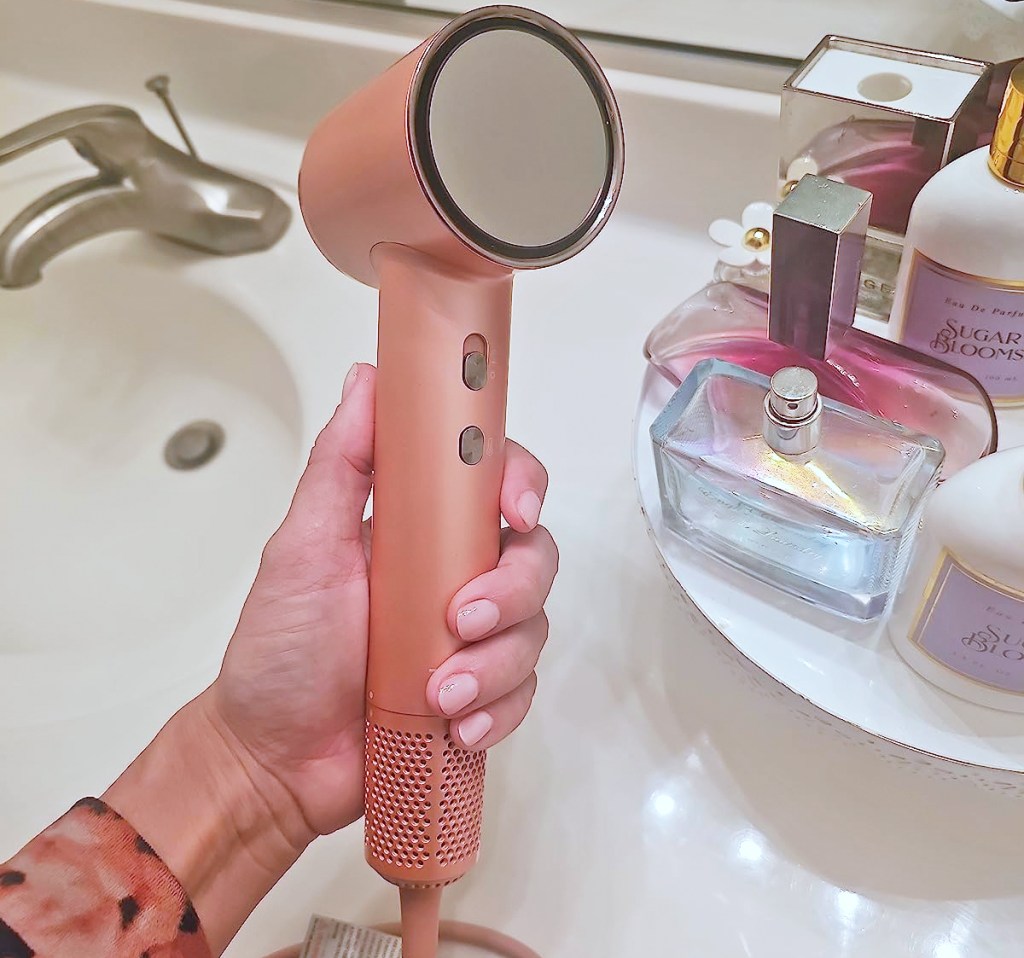 hand holding a pink hair dryer near bathroom sink