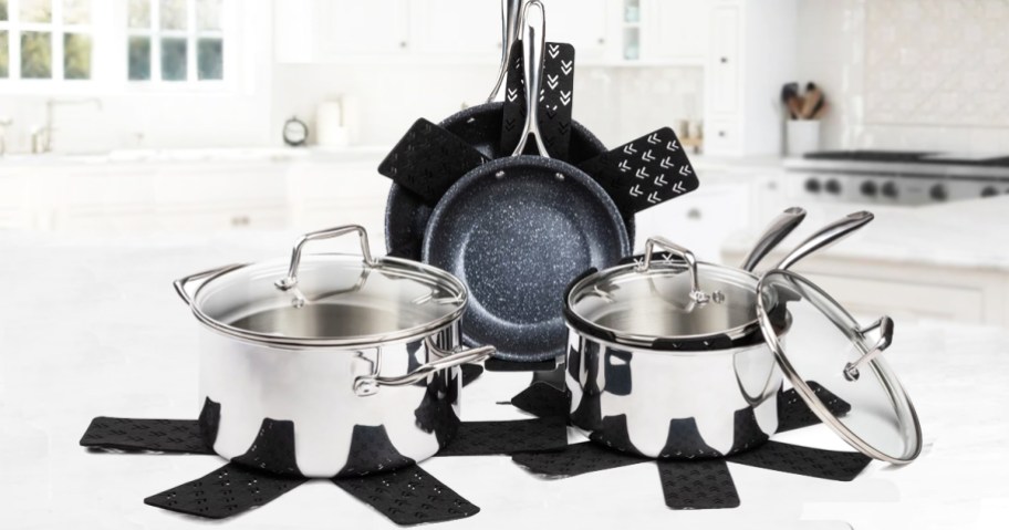 stainless steel cookware set on kitchen counter with pots, pans, and pan protectors