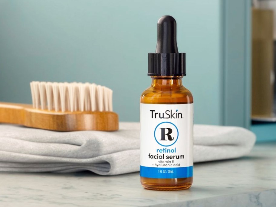 bottle of TruSkin Retinol Serum on bathroom counter near towel and body brush
