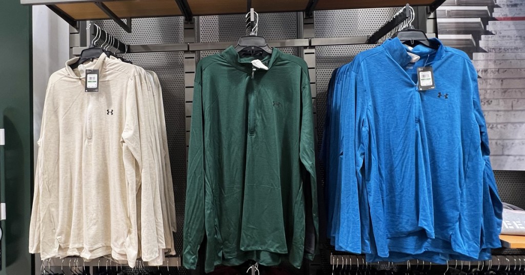 oatmeal, green, and blue under armour halfzips on display in store