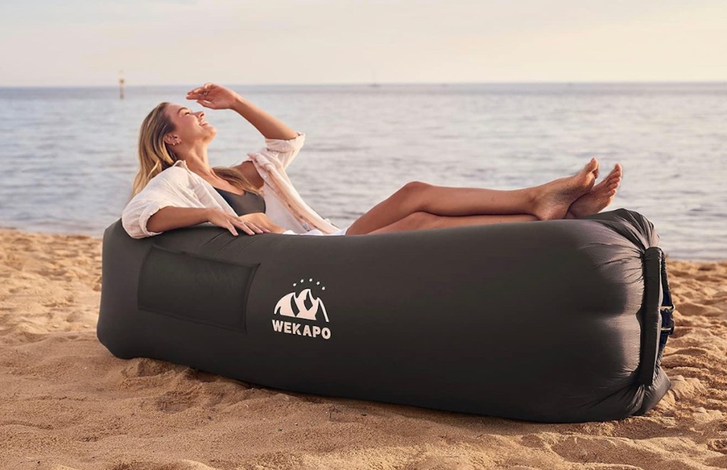 Teen girl sitting in black inflatable chair at beach