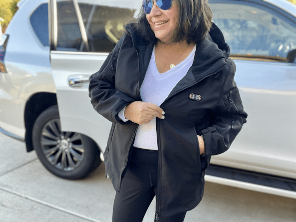 Woman standing outside of car wearing black heated jacket
