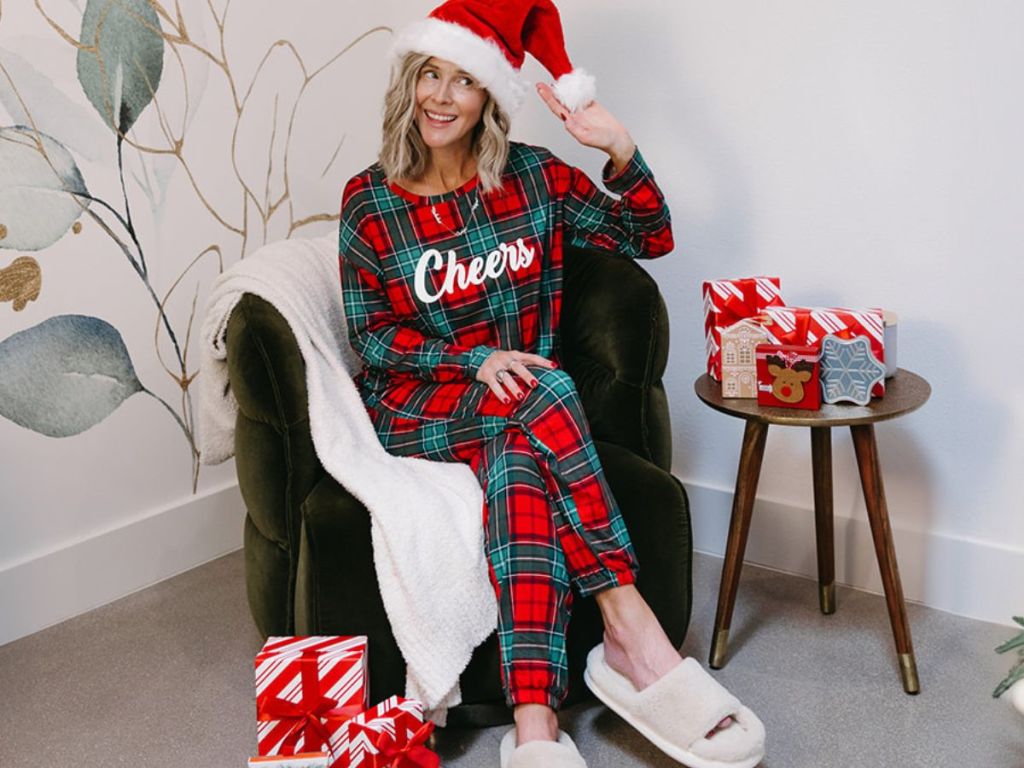 Woman in a santa hat wearing holiday pajamas while sitting in a chair