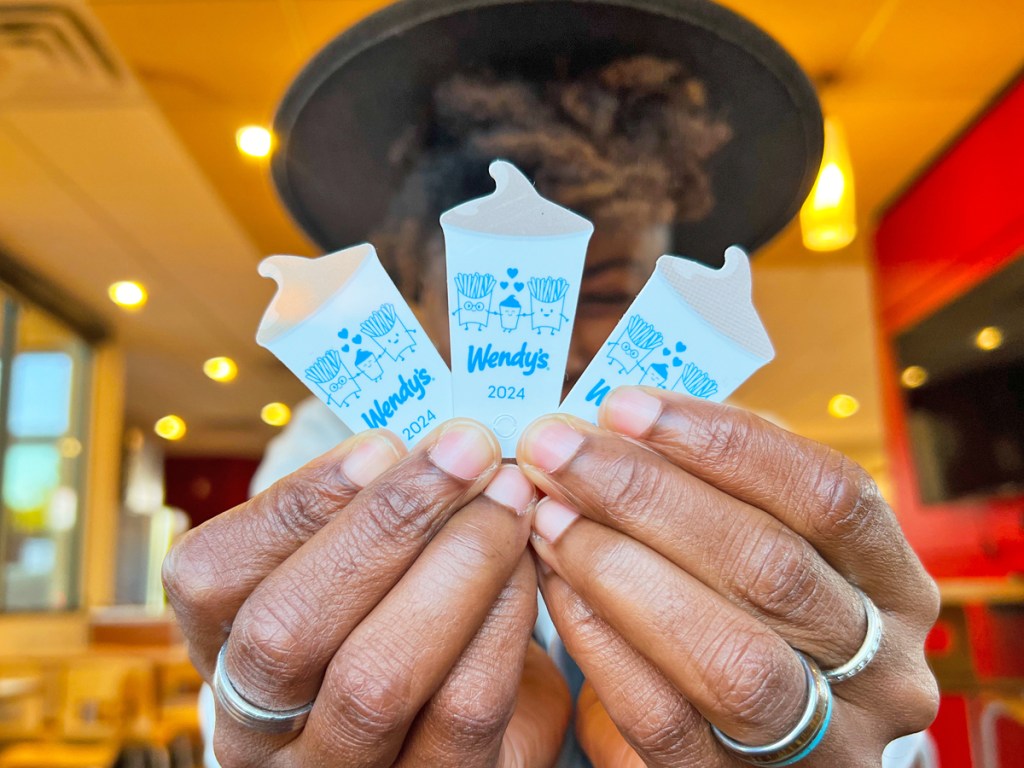 woman holding up three Wendy's frosty key tags