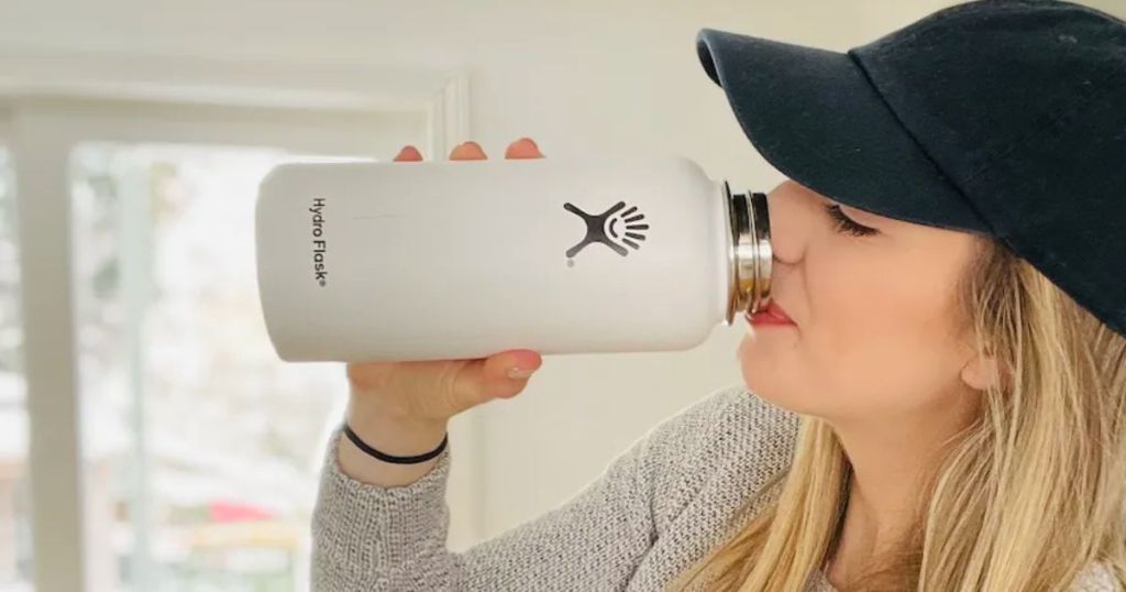 Woman drinking from a white wide mouth hydro flask bottle
