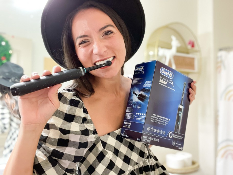 A woman using an Oral B Genius X toothbrush from Amazon