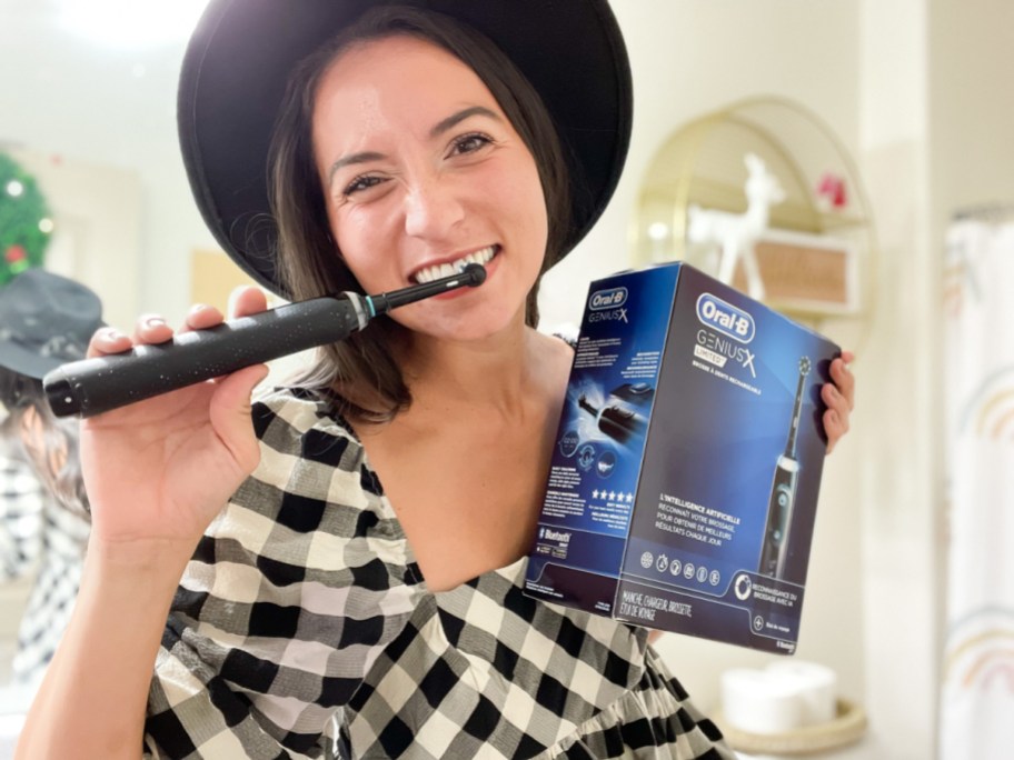 A woman using an Oral B Genius X toothbrush from Amazon