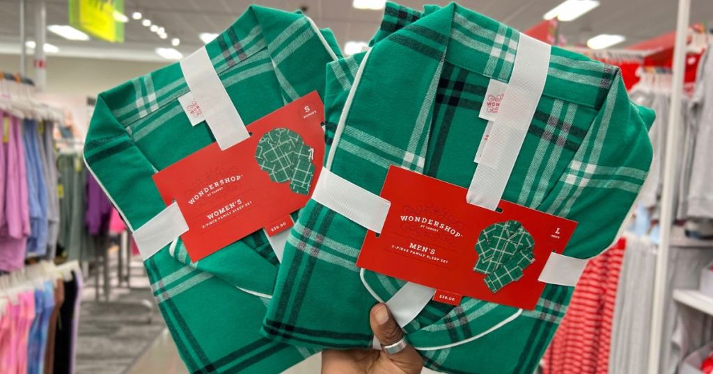 Hand holding up women's and men's matching family Christmas pajamas at Target