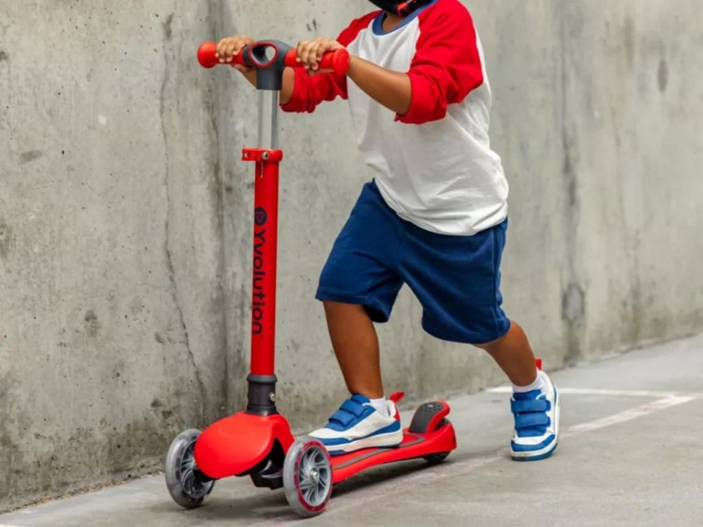 A boy riding a Yvolution Scooter in red