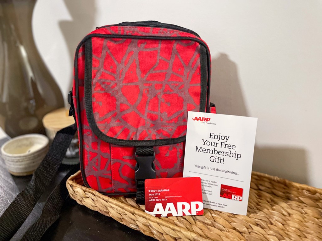 an aarp membership card and pamphlet next to a free crossbody bag gift