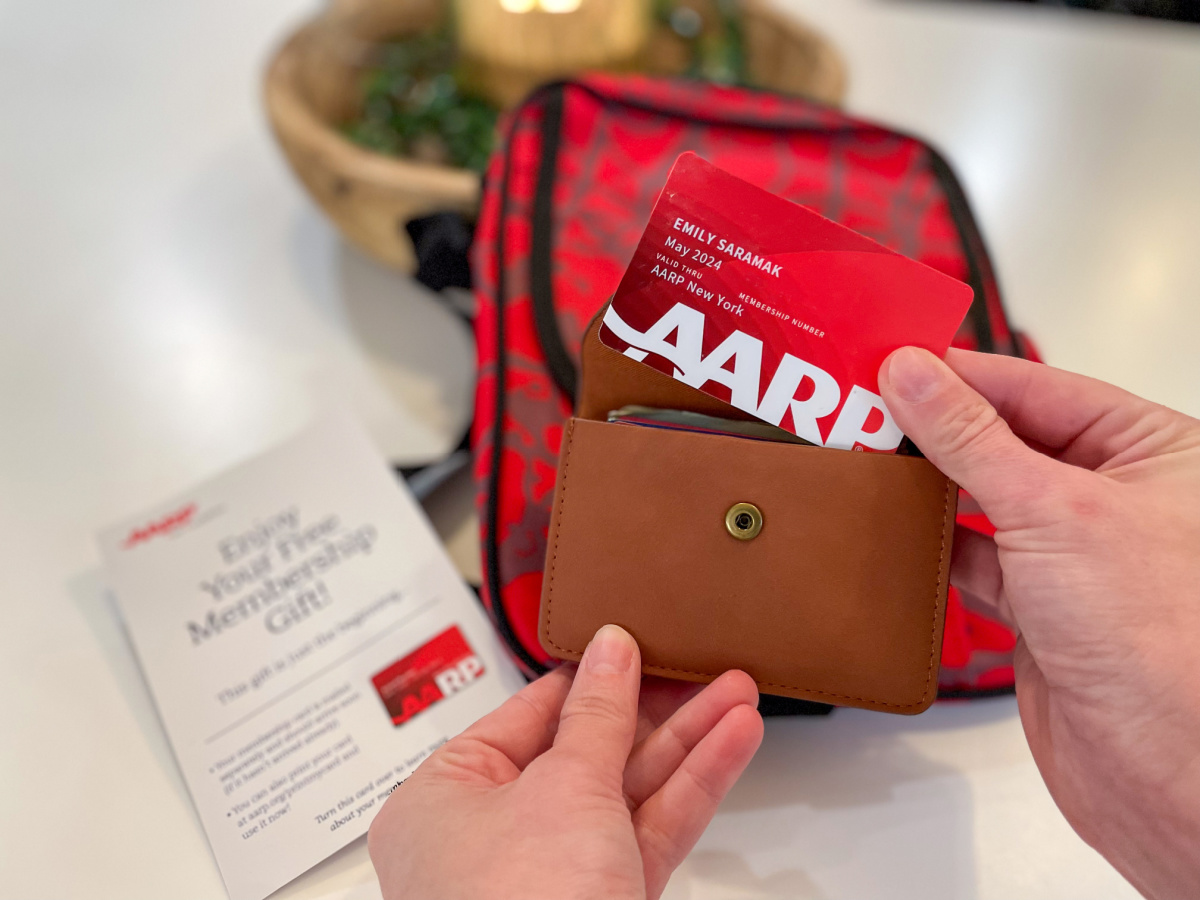 womans hands removing an aarp membership card from a wallet being held above the free crossbody bag gift
