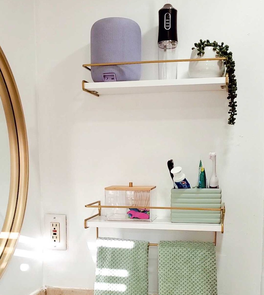 White and gold shelving hanging in bathroom next to mirror