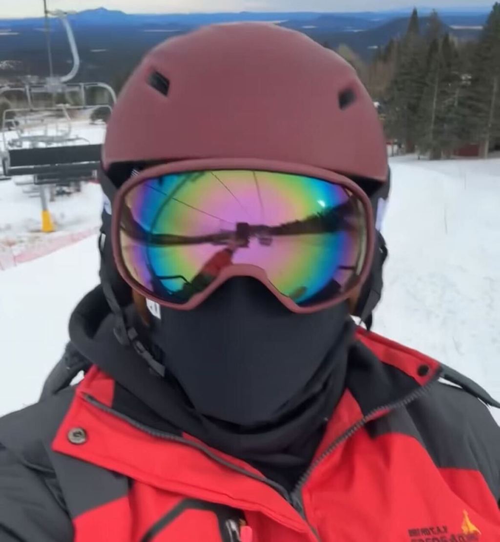 Close-up of person wearing maroon colored ski helmet and matching goggles