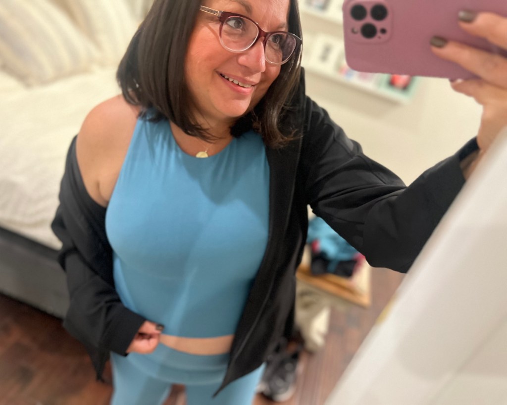 woman holding up phone wearing blue cropped top