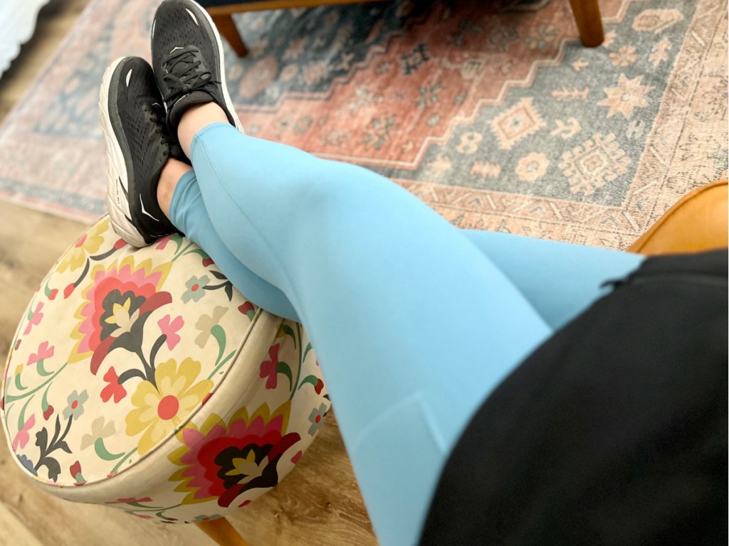 woman with feet on ottoman wearing blue leggings