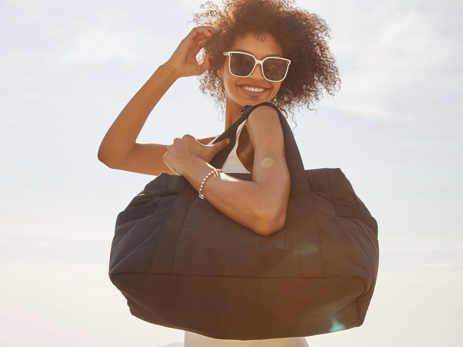 woman holding black travel duffle bag