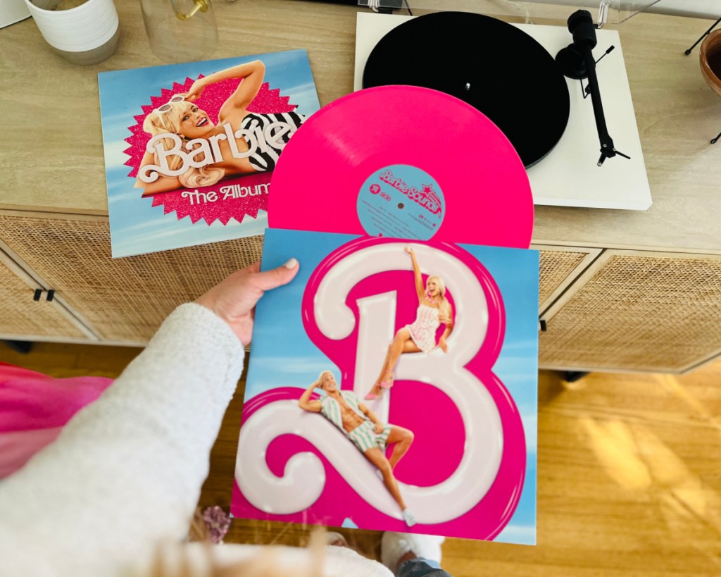 hand holding hot pink barbie vinyl near record player