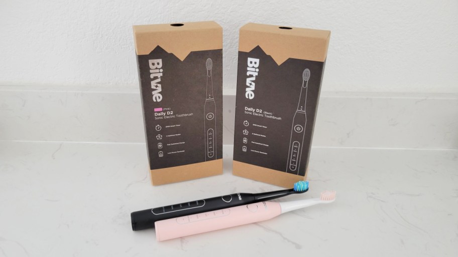 black and pink toothbrushes on counter with boxes