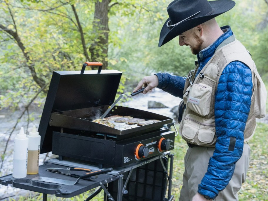 man cooking on blackstone griddle with cowboy hat