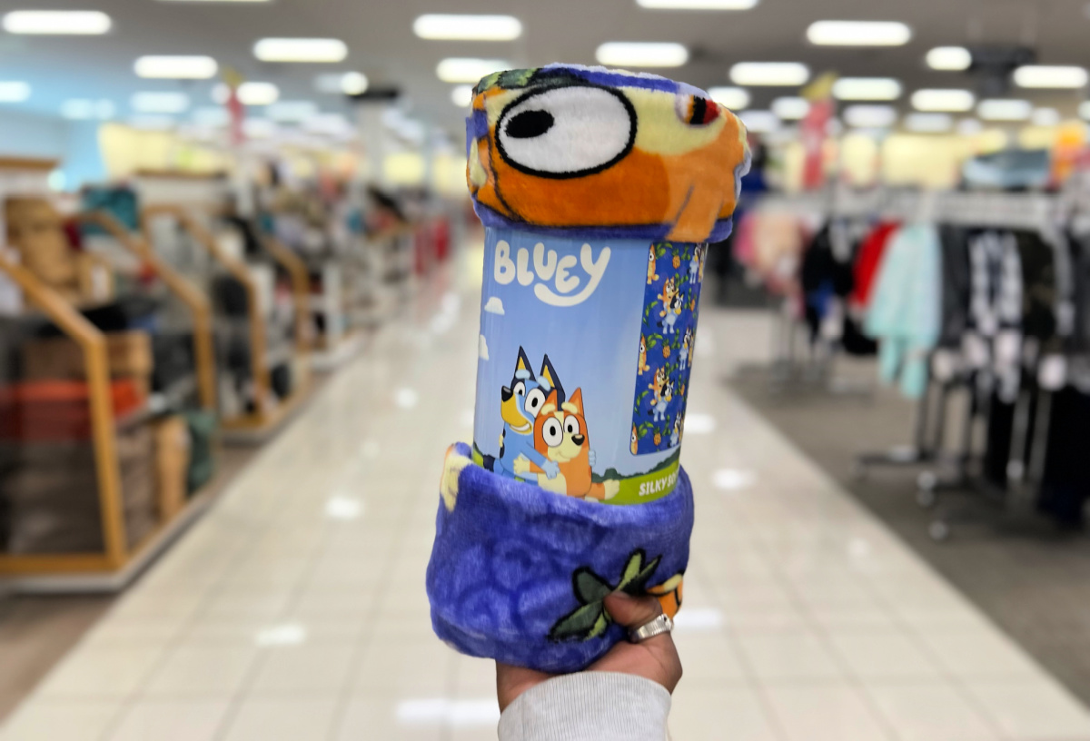 hand holding up a bluey blanket in a kohls store aisle