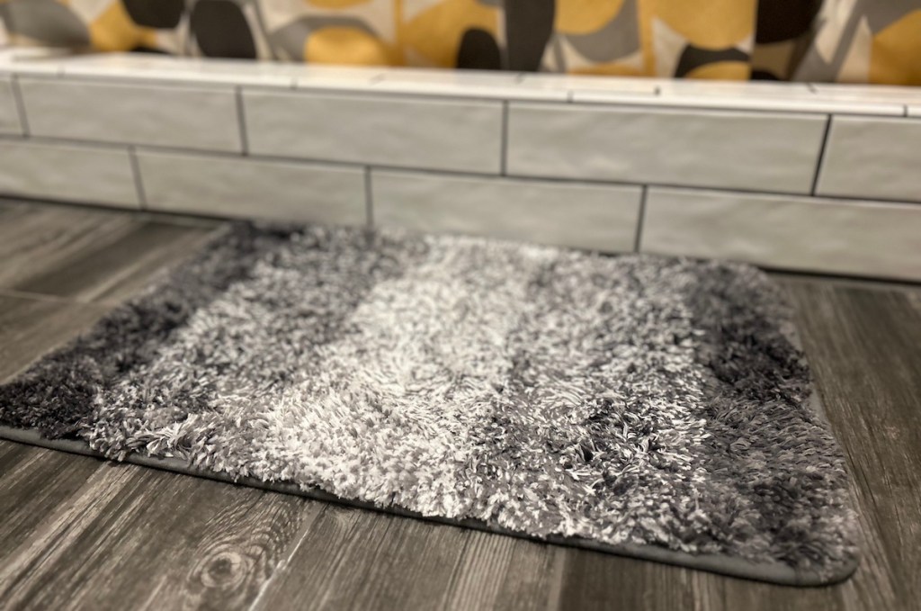 Close-up of gray ombre bath mat on gray tile floor