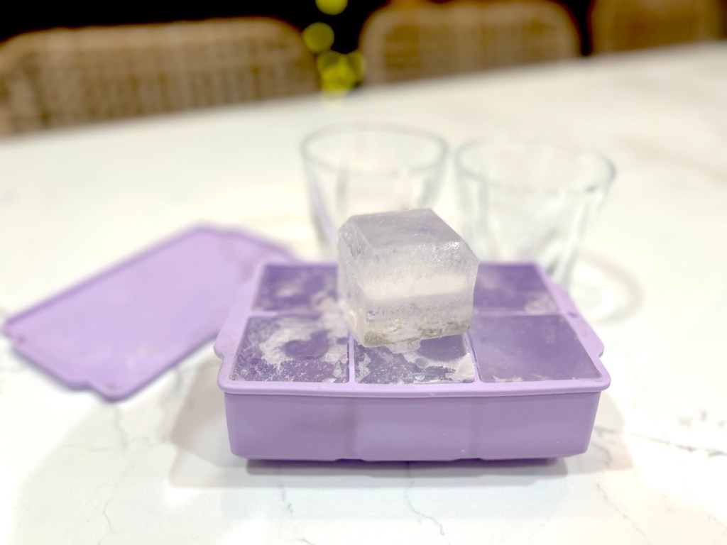 Close-up of purple silicone ice molds with large cube of ice on top