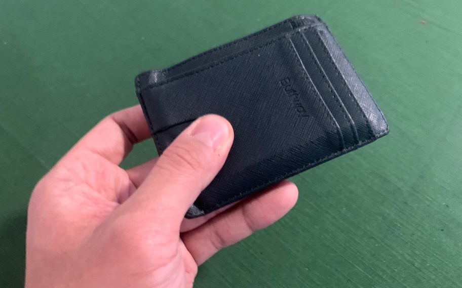 hand holding black leather slim wallet and credit card holders with green background