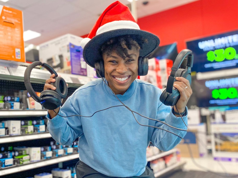 cam holding two pairs of headphones wearing santa hat