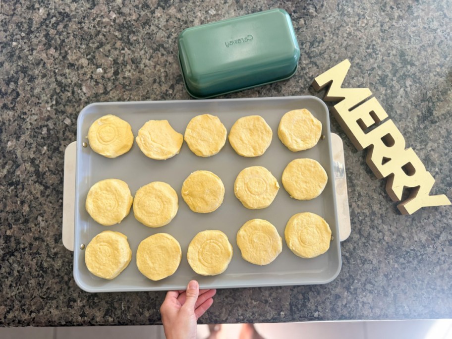 hand holding tray of biscuits next to merry sign