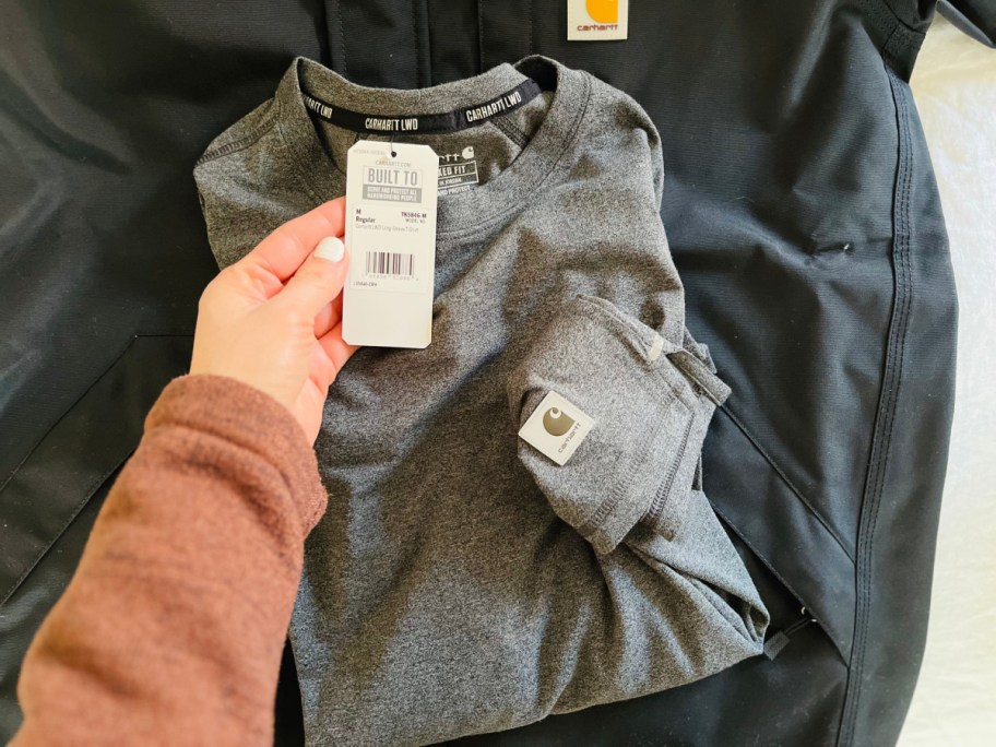 hand holding carhartt tag on shirt