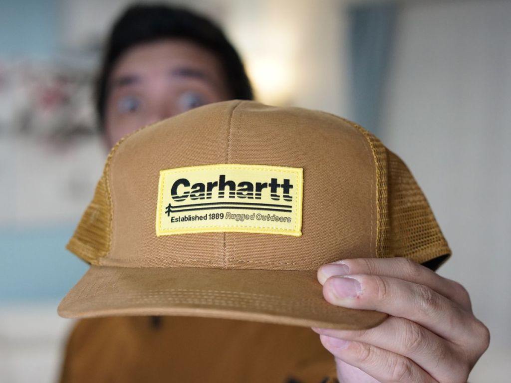 man holding up Carhartt hat