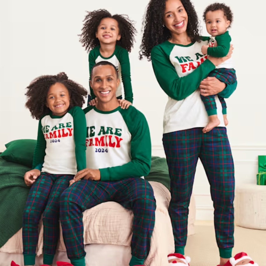 family wearing matching green plaid Christmas pajamas with shirts that say 