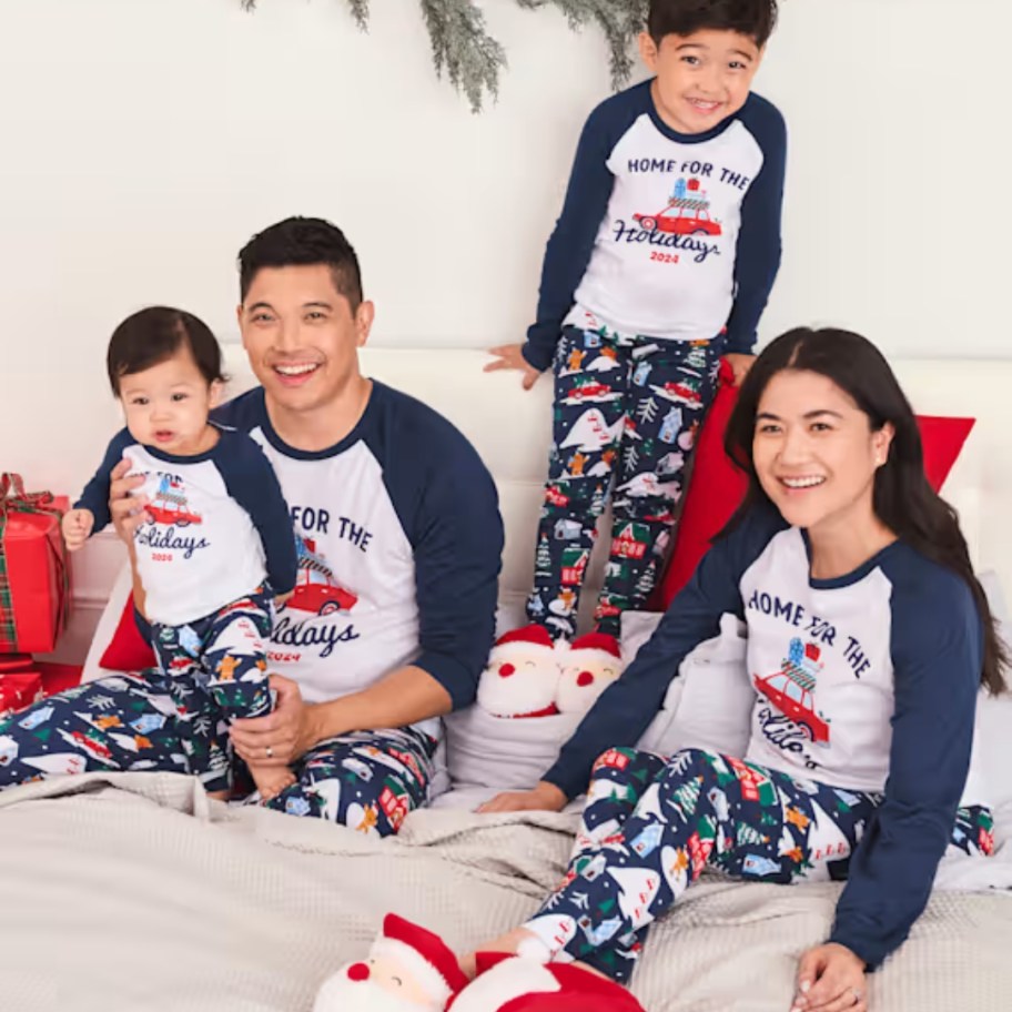 family wearing matching blue, white, red, and green Christmas pajamas with shirts that say 