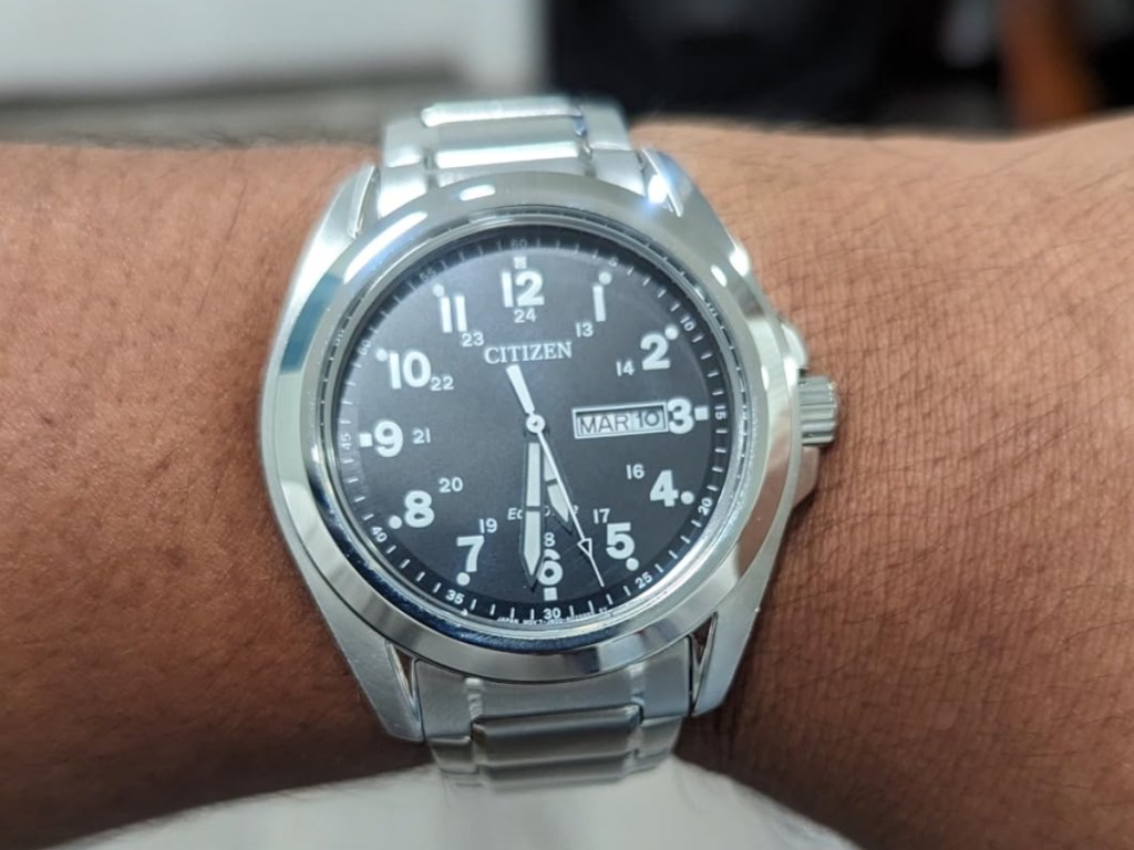 man's wrist wearing silver watch