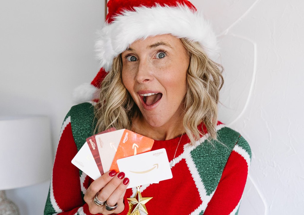 woman wearing christmas outfit holding amazon gift cards